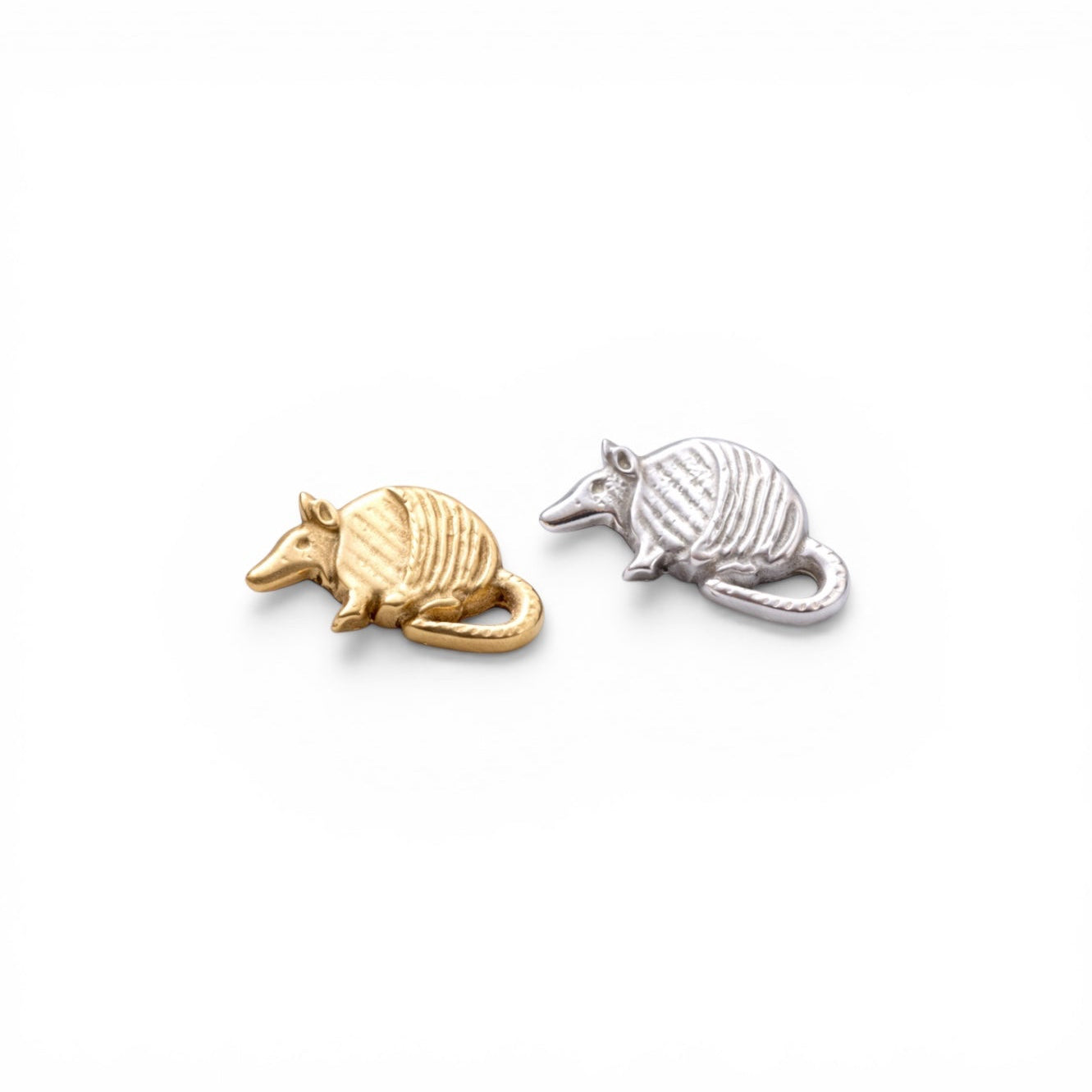 Gold and silver armadillo charms on a white background