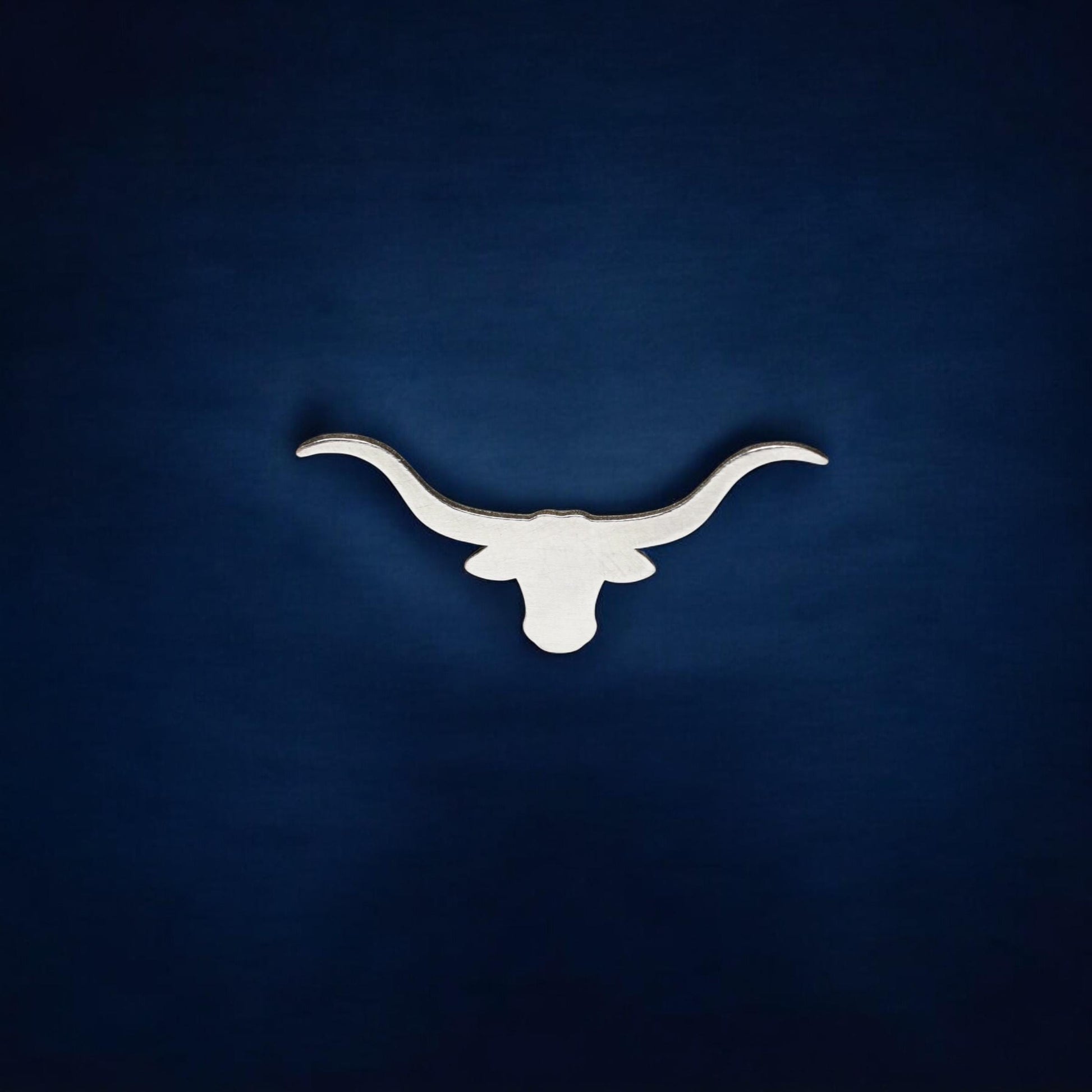 May include: A white silhouette of a longhorn bull&#39;s head with large horns against a dark blue background.